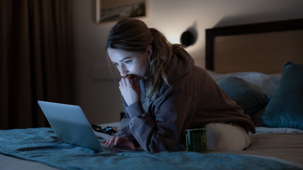 Belle Gibson, interpretada na minissérie Vinagre de Maçã da Netflix, aparece concentrada em um computador, simbolizando sua atuação nas redes sociais enquanto espalhava desinformação