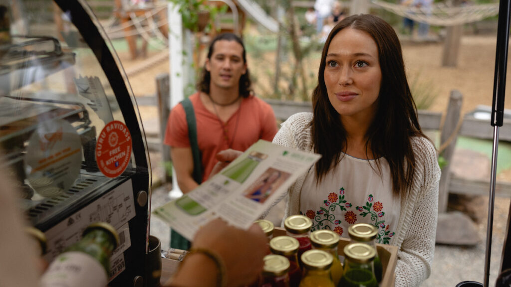 Personagem Milla, da série Vinagre de Maçã da Netflix, vendendo sucos naturais como supostas soluções milagrosas para problemas de saúde