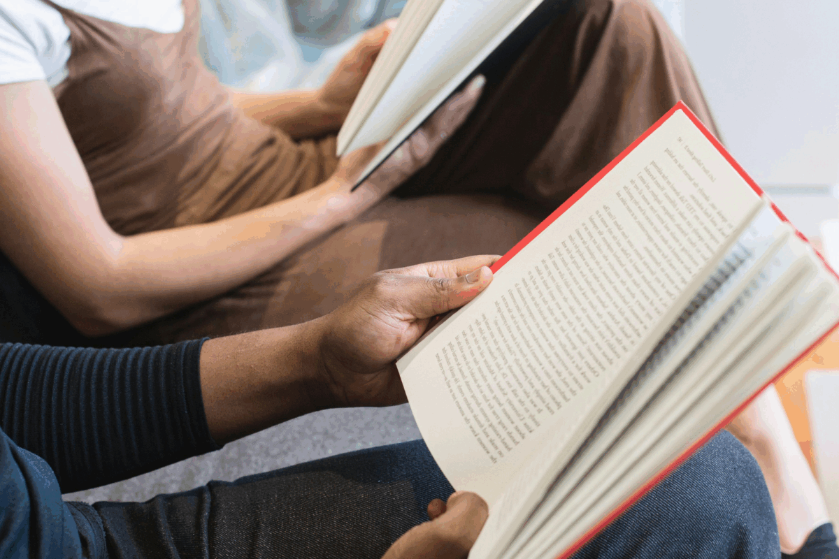 Mãos segurando livros durante um momento de leitura coletiva, conceito inspirado nos clubes do livro silenciosos