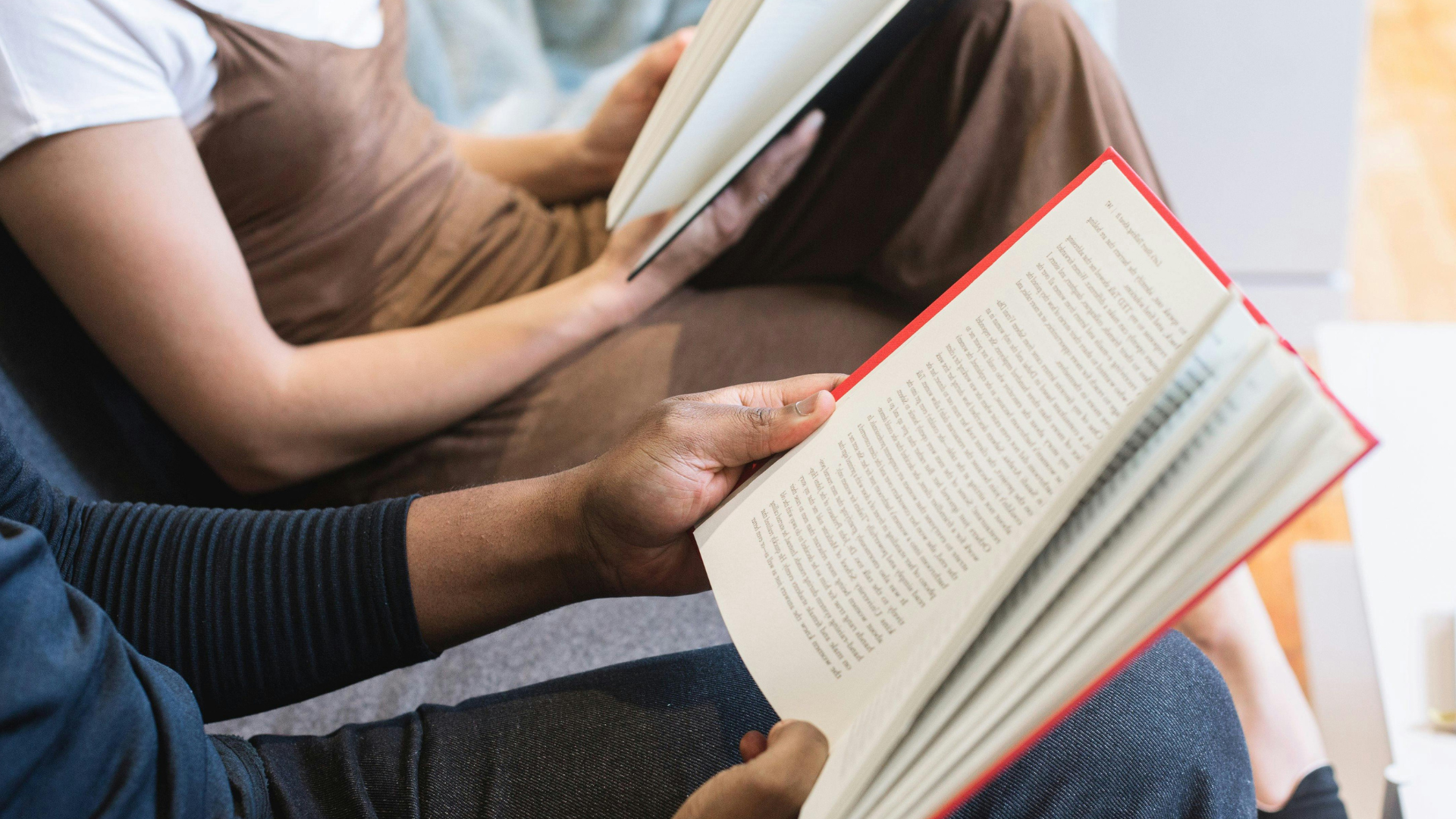 Mãos segurando livros durante um momento de leitura coletiva, conceito inspirado nos clubes do livro silenciosos
